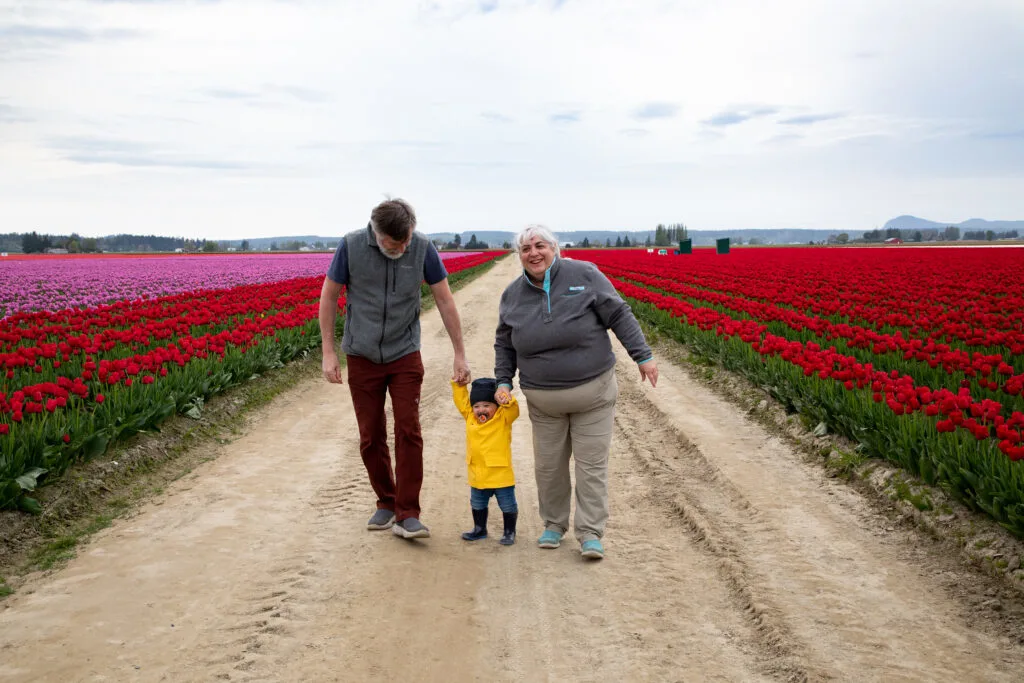 Grandpa Jim and Grandma Corinne walk with AJ through the tulip fields of Washington.